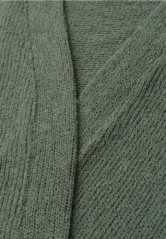 Close-up van een groen gebreide stof met een fijn steekpatroon en zachte textuur.