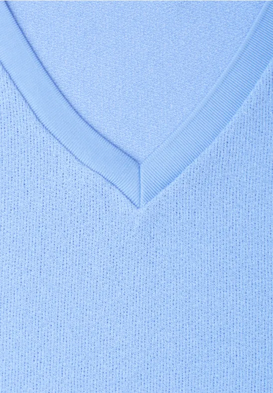Close-up van een lichtblauwe V-hals van fijngebreide stof.