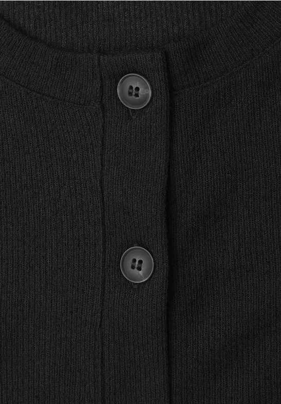 Close-up van een zwarte, geribbelde cardigan met twee ronde knopen aan de voorkant.
