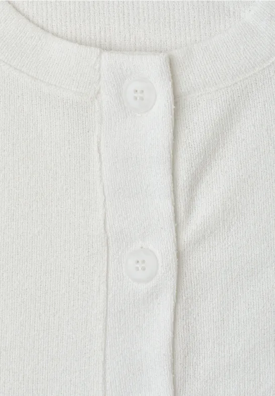 Close-up van een wit T-shirt met knoopsluiting en twee witte knopen.
