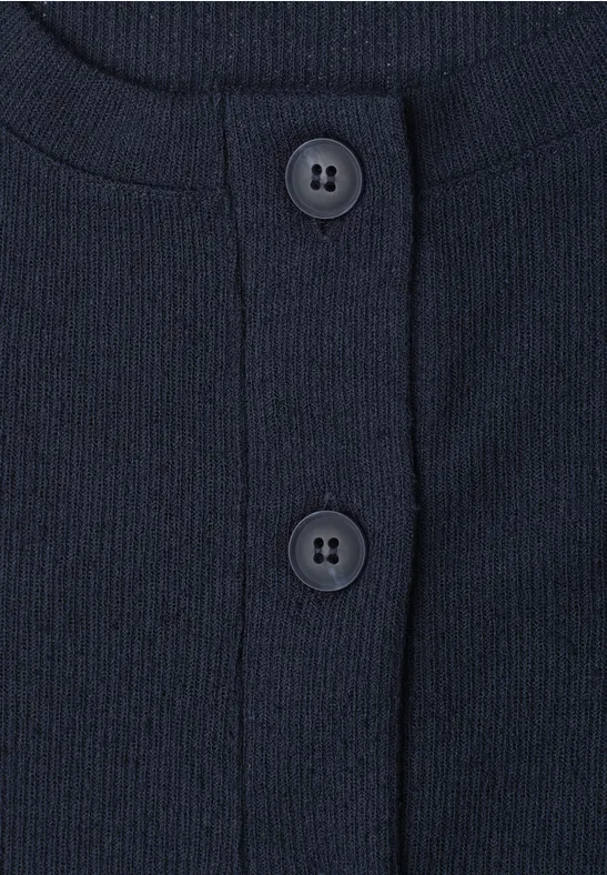 Close-up van een donkerblauw geribd bovenstuk met ronde hals en twee knopen.