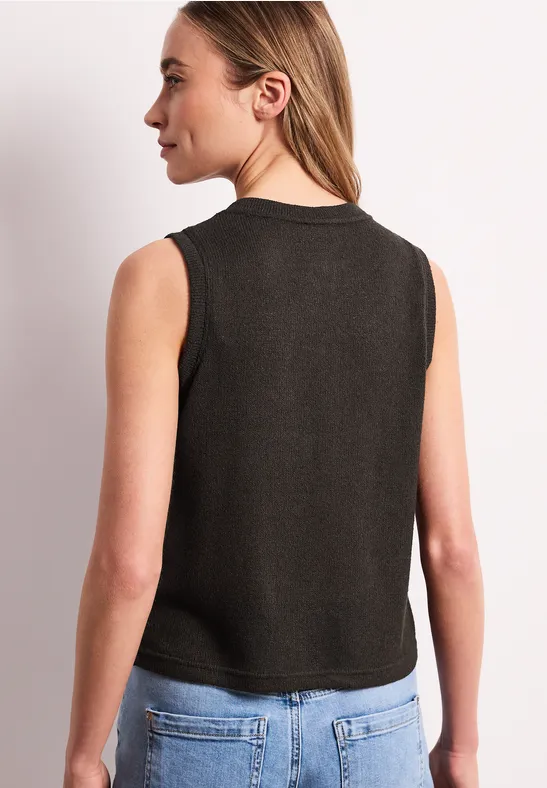 Een vrouw van achteren in een zwart mouwloos topje en lichtblauwe jeans.