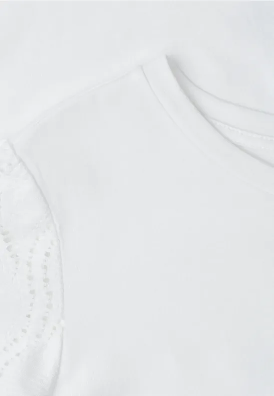 Naheinstellung eines weißen Kinder-T-Shirts mit zarten Spitzenärmeln.