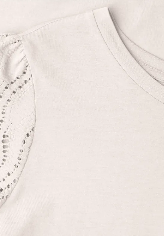 Lichtbeige T-shirt met ronde hals en mouwen versierd met glinsterende studs.