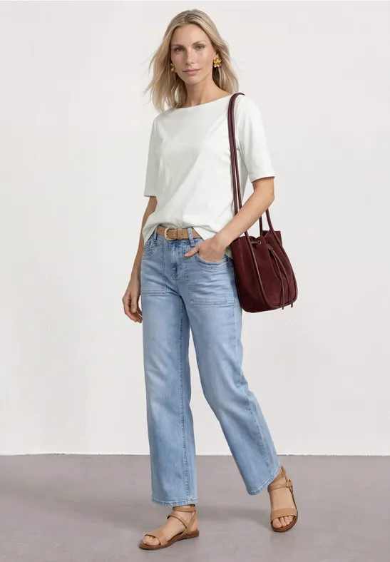 Femme en t-shirt blanc, jean clair, sandales et sac bandoulière rouge.