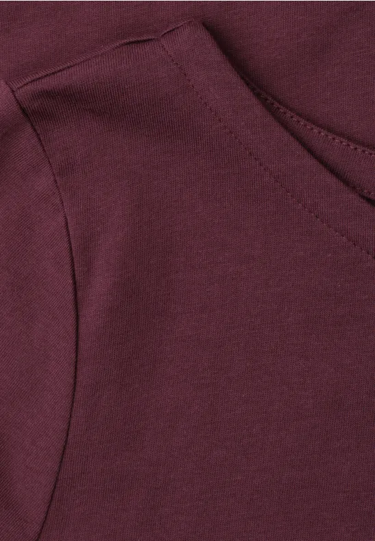 Close-up van de aangebrachte zak op een bordeauxrode hoodie.
