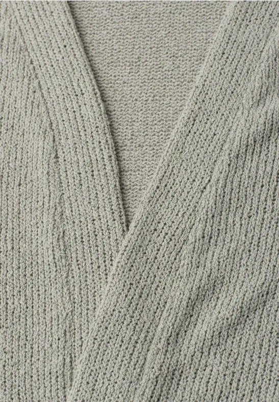 Nahaufnahme eines grauen, gestrickten Cardigans mit überkreuztem V-Ausschnitt.