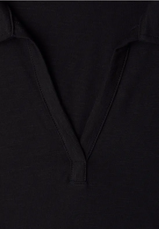 Schwarzes Stoffdetail mit V-förmigem Ausschnitt, vermutlich Teil eines T-Shirts oder Poloshirts.