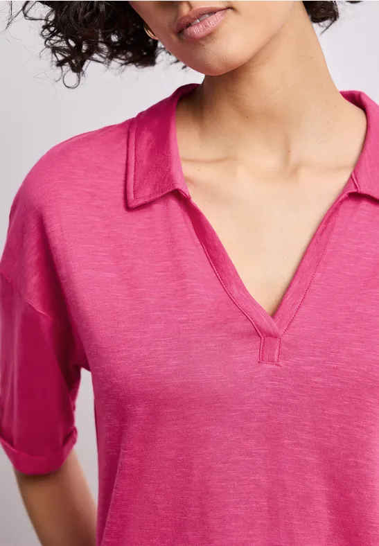 Frau trägt locker sitzendes pinkes V-Ausschnitt-Shirt mit Hemdkragen und halblangen Ärmeln