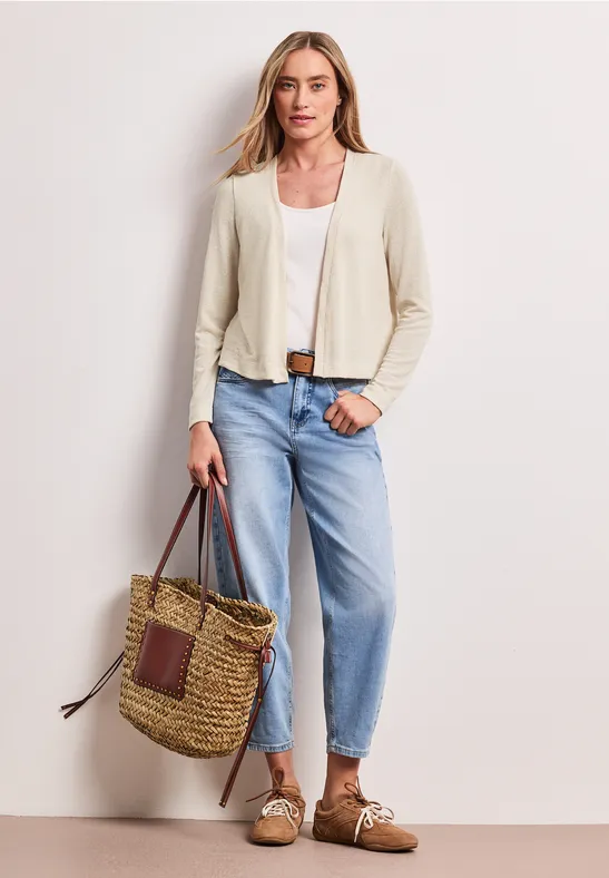 Vrouw in beige blazer, wit shirt, lichtblauwe jeans, mocassins en een strooien tas in casual stijl.