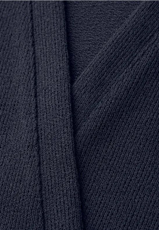 Close-up van donkerblauw geribbeld gebreid textiel met overlappende rand.