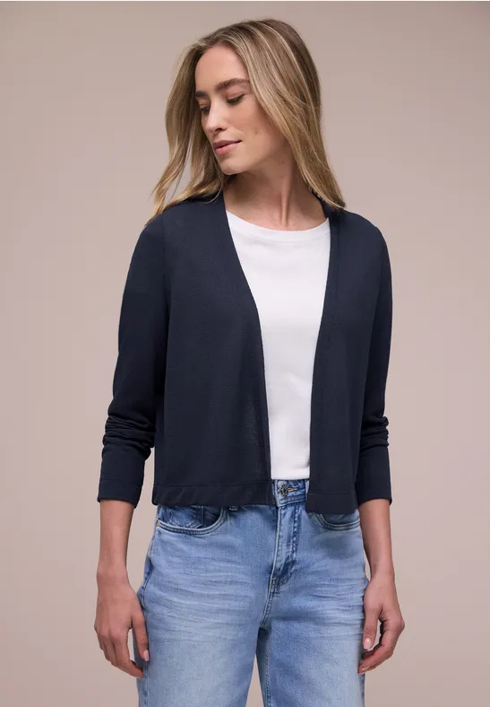 Vrouw met wit T-shirt, donkerblauw vest en lichte spijkerbroek.