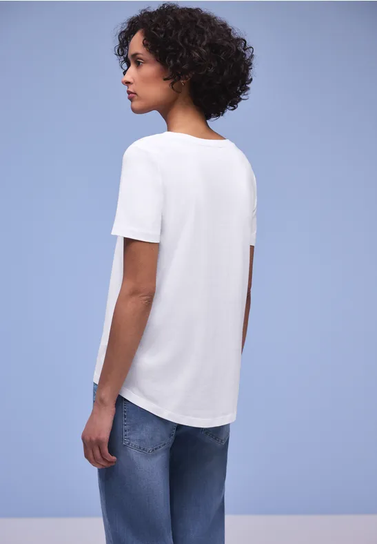 Achteraanzicht van persoon in wit T-shirt en blauwe spijkerbroek tegen lichte achtergrond.