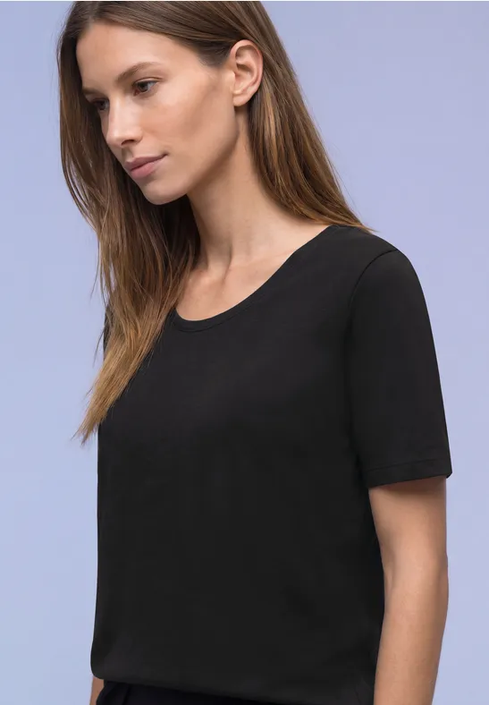 Frau in schlichtem schwarzem T-Shirt, aus seitlicher Perspektive