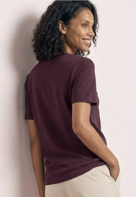 Persoon van achteren in bordeauxrode t-shirt en lichte broek