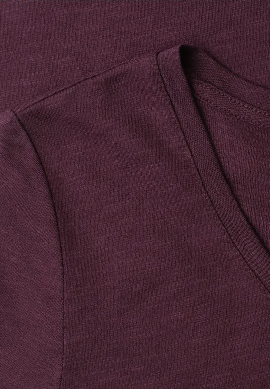 Close-up van een donkerrood T-shirt met ronde hals en fijne stofstructuur.