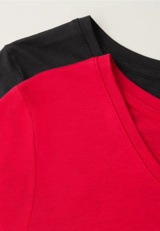 Ein rotes V-Ausschnitt-T-Shirt liegt auf einem schwarzen T-Shirt.