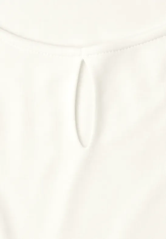 Weißes Kleidungsstück mit kleinem, ovalem Ausschnittdetail am Rundhalsausschnitt.