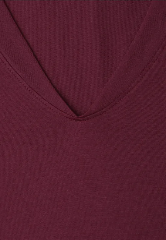 Nahaufnahme eines burgunderfarbenen V-Ausschnitt-T-Shirts aus Baumwolljersey.