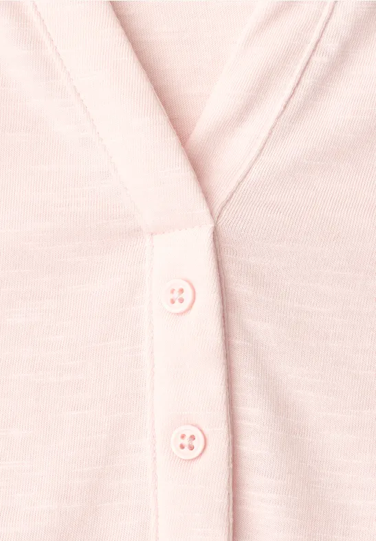 Nahaufnahme eines hellrosa Cardigans mit Knopfleiste
