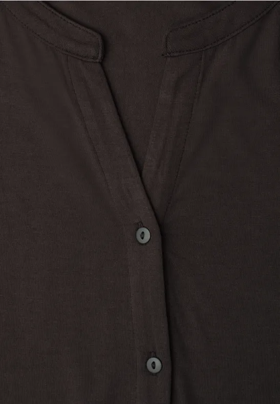 Nahaufnahme eines dunklen Hemds mit V-Ausschnitt und zwei Knöpfen