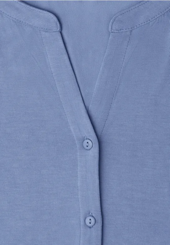 Hellblaues Baby-Oberteil mit Knopfleiste am Halsausschnitt.