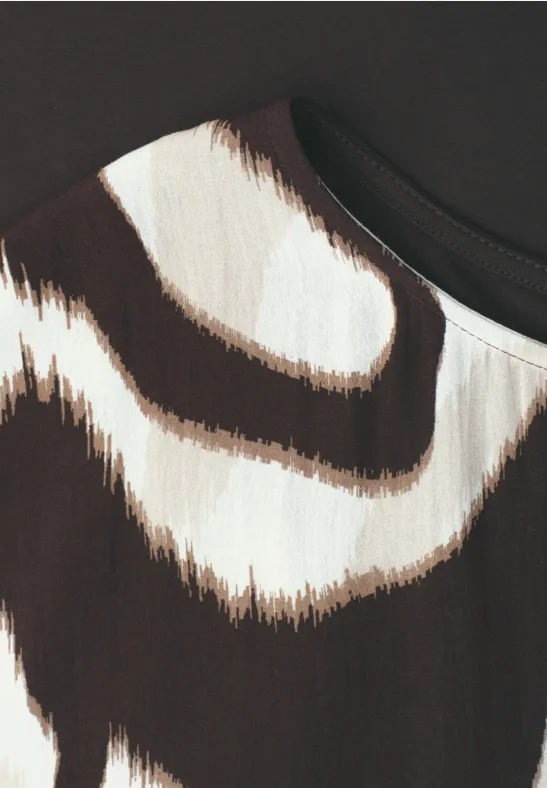 Nahaufnahme eines Stoffmusters mit unregelmäßigen braun-beigen Streifen auf hellem Grund.