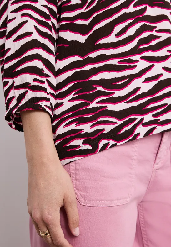 Person mit rosa-schwarz-weiß gestreiftem Zebratop und rosa Hose, Hand mit Ring sichtbar