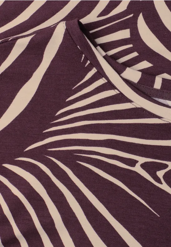 Close-up van een paarse top met crèmekleurige, abstracte zebraprint.