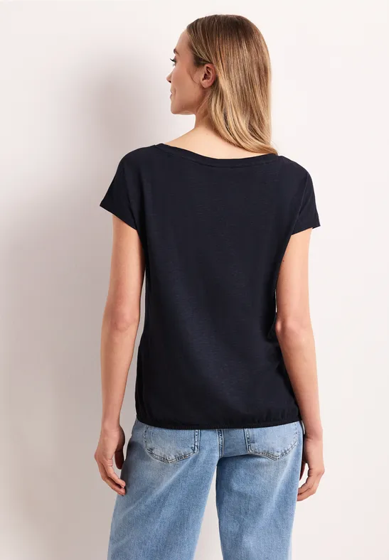 Vrouw van achter gezien met zwart T-shirt en blauwe spijkerbroek.