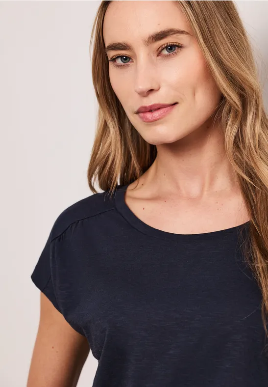 Vrouw met vervaagd gezicht in een eenvoudig, donker T-shirt voor een lichte, neutrale achtergrond.