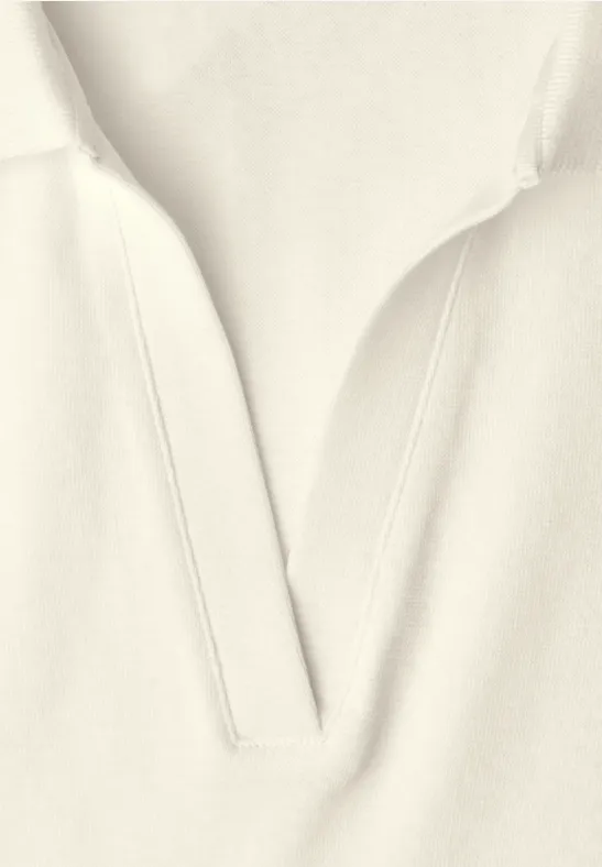 Gros plan sur vêtement beige clair avec encolure en V et coutures discrètes.