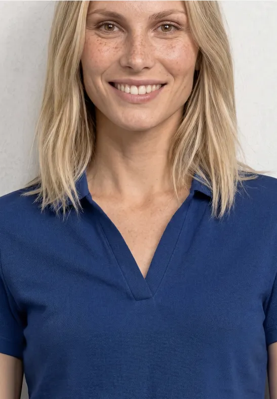 Femme aux cheveux blonds portant un polo bleu, visage flou.