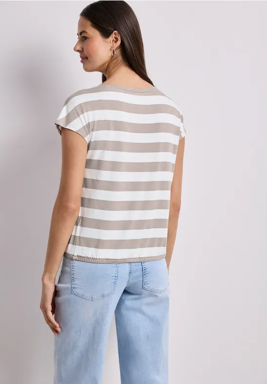 Femme de dos portant un t-shirt à rayures et un jean clair.