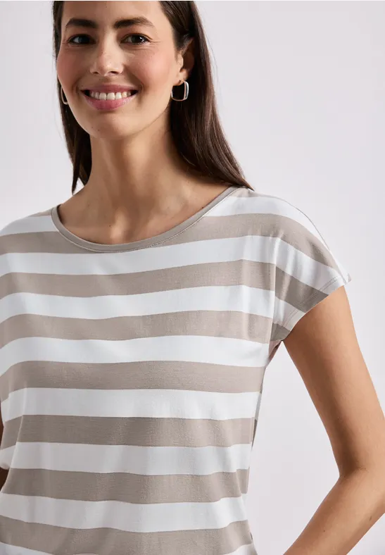 Une femme souriante portant un T-shirt à rayures blanche et beige sur fond clair.