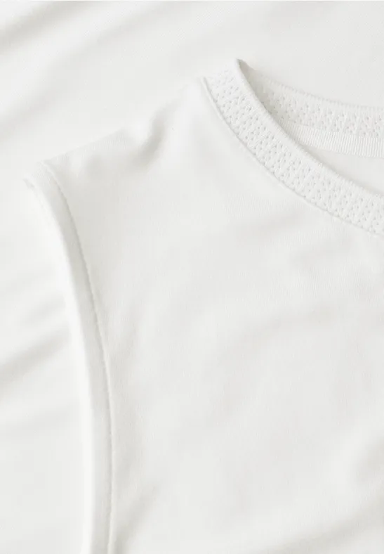 Close-up van een wit mouwloos katoenen T-shirt met fijne textuur.