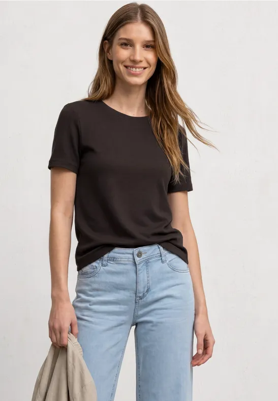 Une femme porte un t-shirt noir simple et un jean bleu clair.