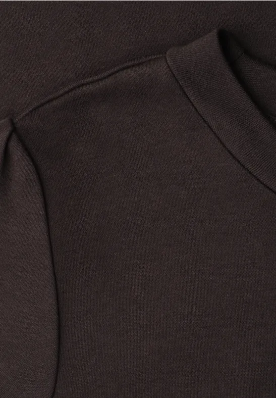 Gros plan d'un sweat à capuche brun foncé mettant en valeur une poche et une couture.