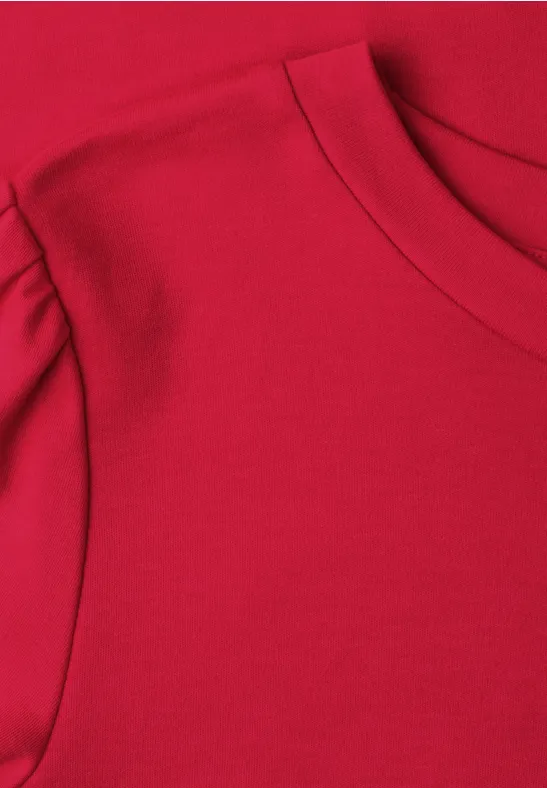 Close-up van een rood T-shirt met ronde hals en doorlopende schoudernaad