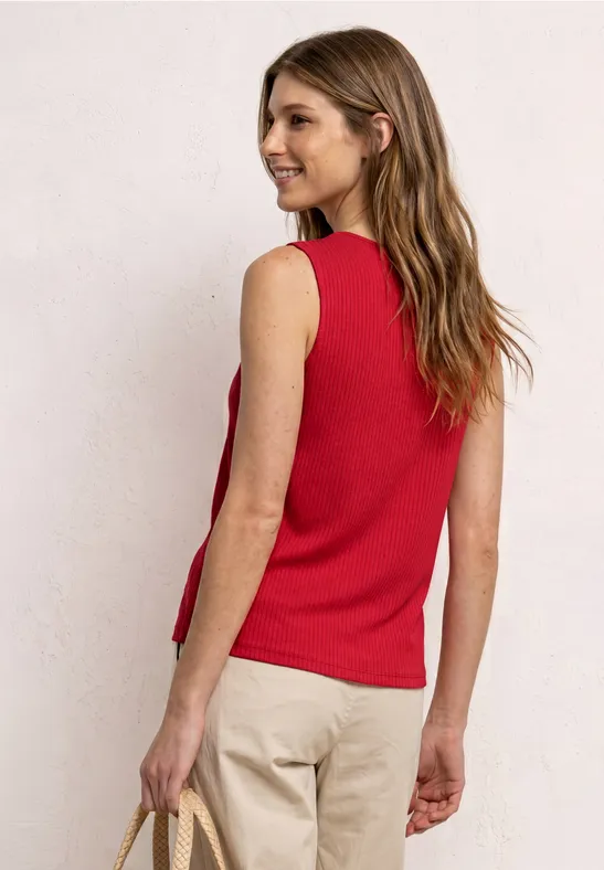 Vrouw van achter in rood mouwloos shirt, lichte broek en tas