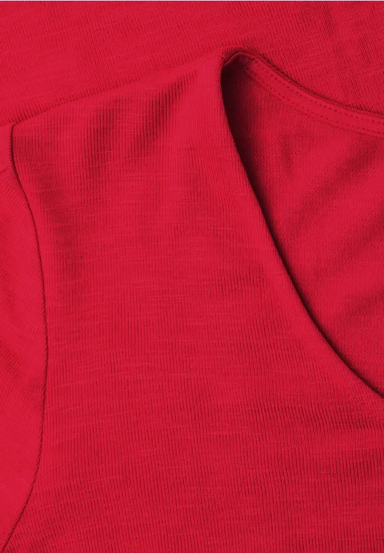 Close-up van een rode mouwloze top met ronde hals en fijne textuur.