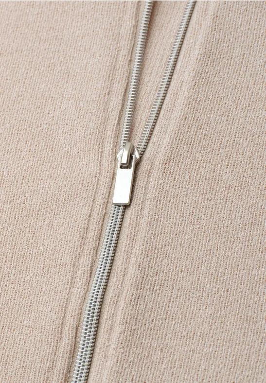 Gros plan d'un tissu beige tricoté avec une fermeture éclair argentée au centre