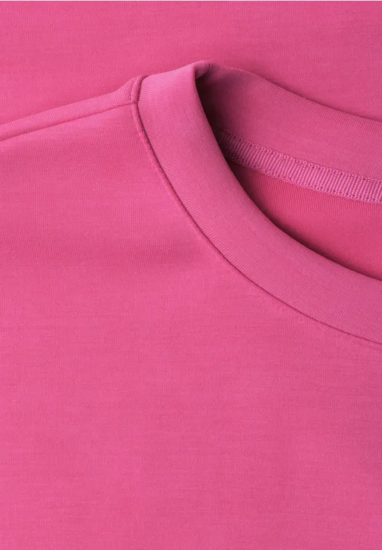 Close-up van een roze T-shirt met ronde hals.