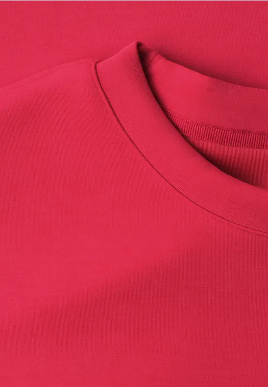 Een effen rood T-shirt met ronde hals, alleen de kraag en het bovenste deel zichtbaar.