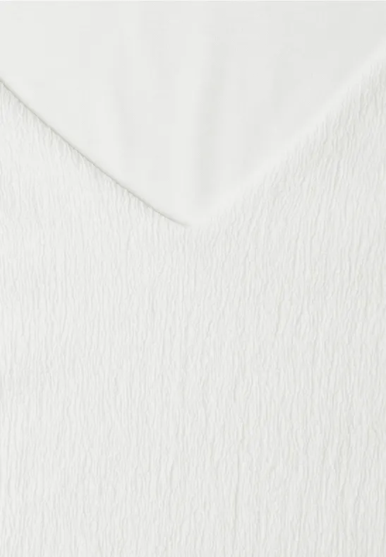 Gros plan sur un tissu blanc texturé avec un pli en V.