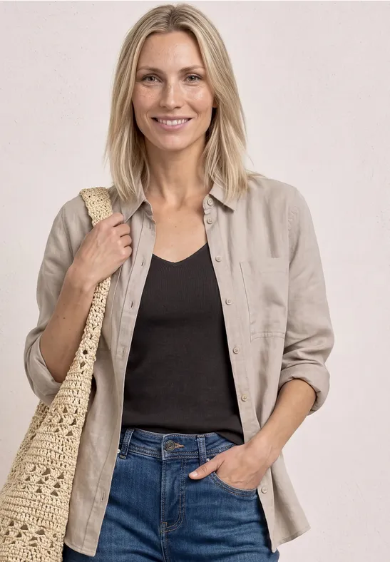 Vrouw in spijkerbroek, zwart hemd, beige blouse en strozak