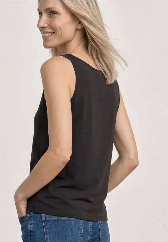 Vrouw gezien van achter met een zwarte tanktop en een blauwe spijkerbroek.