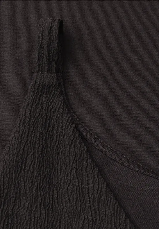 Close-up van zwart topje met fijne, geribbelde textuur op het bandje.