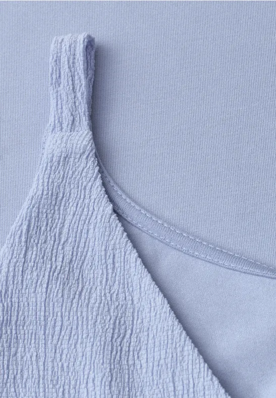 Close-up van een lichtblauw spaghettihempje met gestructureerde stof.