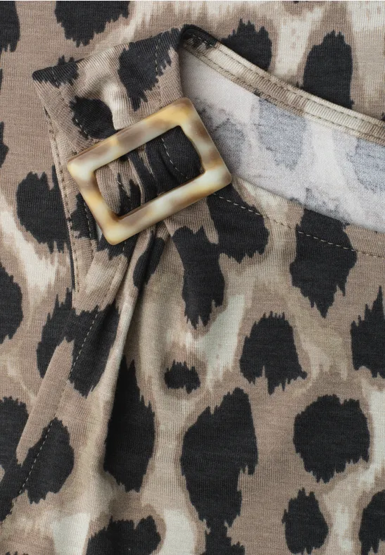 Gros plan d'une ceinture à boucle dorée et motif léopard sur tissu.